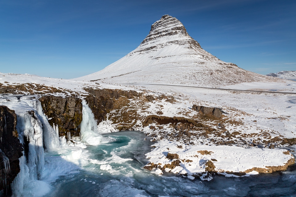 Kirkjufell mountain and its frozen waterfalls in winter